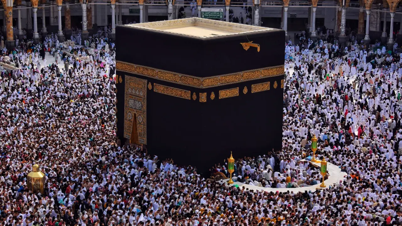 Panoramic high-angle view of the Kaaba during Tawaf, highlighting the Rukn al-Aswad (Black Stone Corner) with pilgrims moving like white waves.